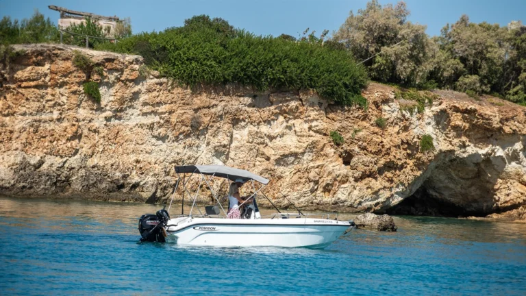 a poseidon 470 boat cruising next to rock cliffs